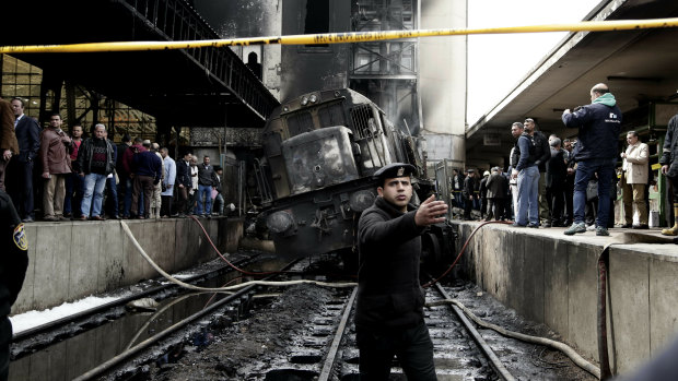 Police guard the front of a damaged train inside Ramses train station in Cairo, Egypt.