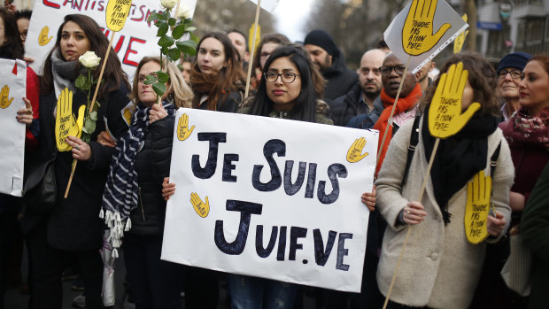 A woman carries a poster reading "I am a jew" as she attends a silent march to honour an 85-year-old woman who escaped the Nazis 76 years ago but was stabbed to death in her Paris apartment in March, apparently because she was Jewish.
