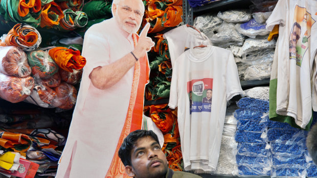 A customer sits in front of a cut-out of India's Prime Minister Narendra Modi in a store selling election merchandise at the Sadar Bazaar market in New Delhi.