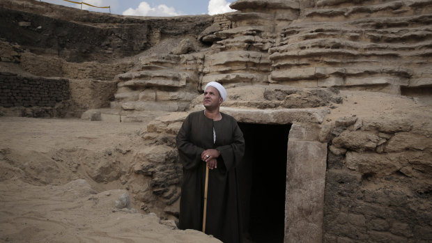 The leader of the excavation stands in front of a newly discovered tomb.