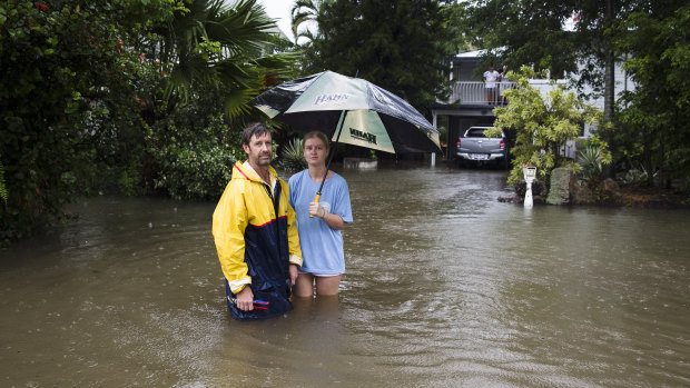 Local resident Paul Shafer and daughter Lily standing in floodwaters in Hermit Park, Townsville, on Saturday. They made the decision to evacuate later in the day.