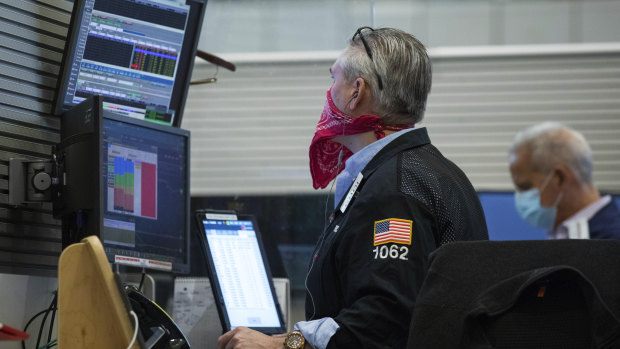 Stock traders wearing masks and bandanas keep a close eye on data as it comes in.
