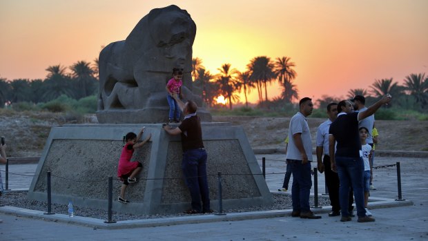 People stand near the Lion of Babylon at the archaeological site of Babylon, Iraq, on Friday.