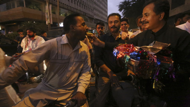 Supporters of Pakistan's Tahreek-e-Insaf party, headed by Imran Khan, offer sweets to celebrate Khan's election on Friday.