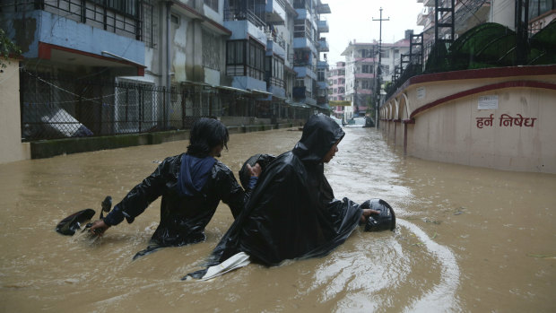 A Nepalese pulls his motorbike and wades past a flooded street in Kathmandu, Nepal, on Friday.