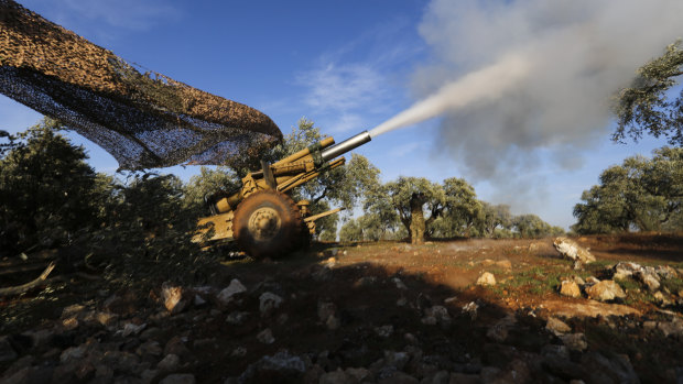 Turkish backed rebel fighters fire a howitzer towards the Syrian government forces' positions near the village of Neirab in Idlib province, Syria, on Thursday.