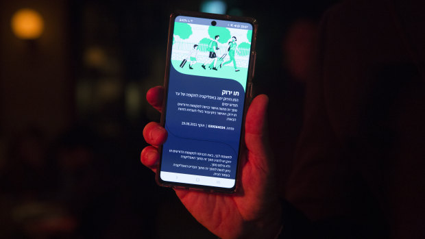 An Israeli man holds his smart phone as he is presenting a ‘Covid19’ vaccination certificate named ‘Green Pass’, before entering a bar in Tel Aviv, Israel. 