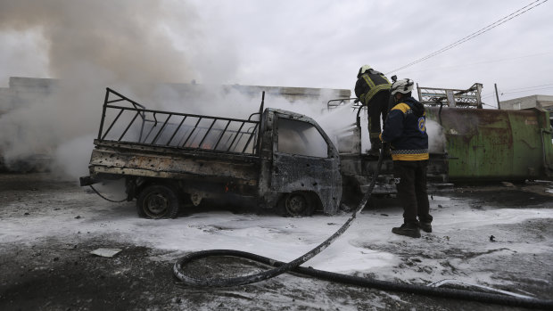 Firefighters hose a truck after a Syrian government air strike in the city of Idlib on Tuesday.