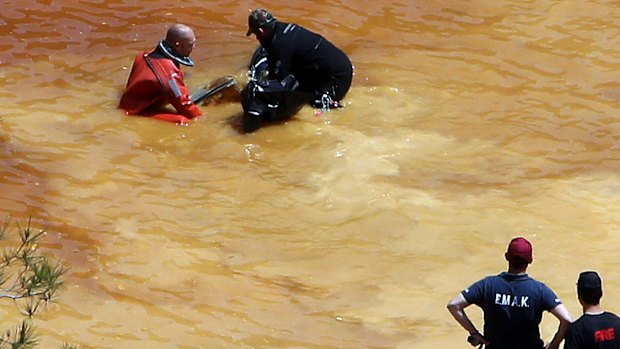 A diver removes a suitcase found in the man-made mining lake on Sunday.