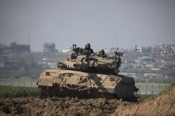 An Israeli tank moves along the border, as Gaza is seen behind in southern Israel.