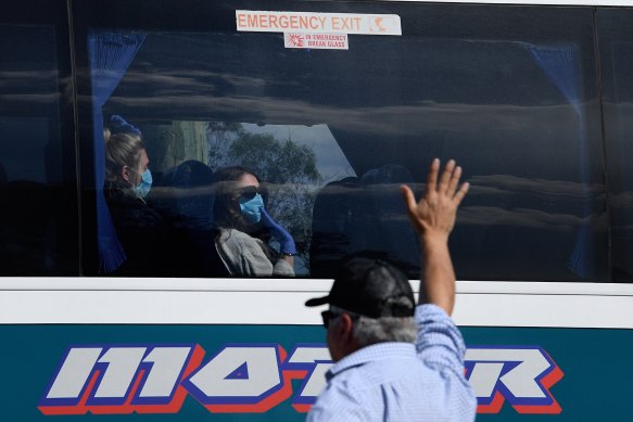 Ruby Princess crew members wave from a bus as it leaves Port Kembla on Tuesday.