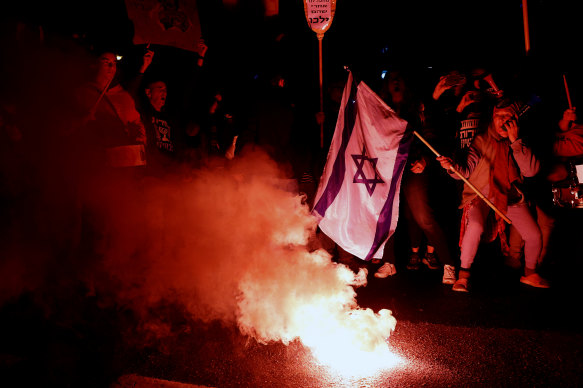 Protesters use a smoke torch during a demonstration calling for a hostages deal and against the Israeli government on February 17, 2024 in Tel Aviv, Israel. 