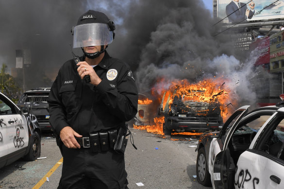 Los Angeles Police Department commander Cory Palka stands among several destroyed police cars.