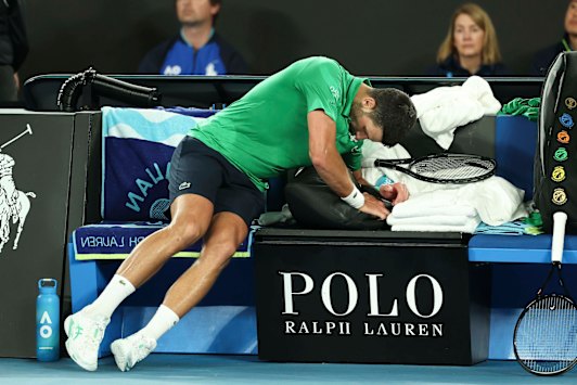 Rafael Nadal gesturing during a press conference at Melbourne Park, surrounded by media microphones against a blue backdrop.