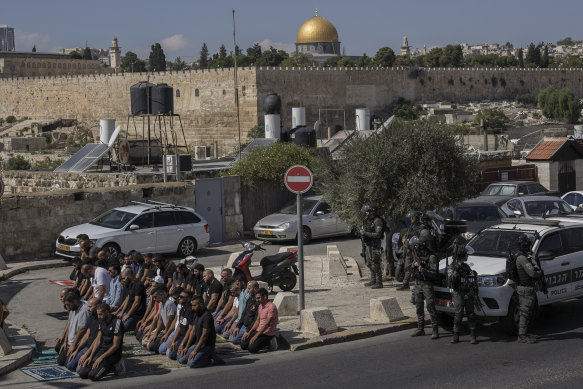 Palestinian worshippers pray outside Jerusalem’s Old City while Israeli forces stand guard on Friday.