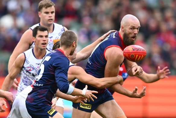 Max Gawn of the Demons handballs whilst being tackled.