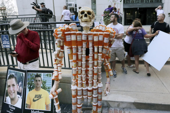 A skeleton made of pill bottles stands with protesters outside a courthouse in Boston, where a judge was hearing arguments against opioid maker Purdue Pharma.