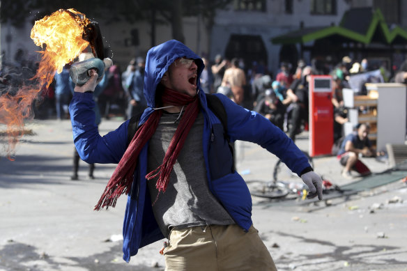 An anti-government protester throws a firebomb at police during a march by students and union members in Santiago, Chile, on Monday.