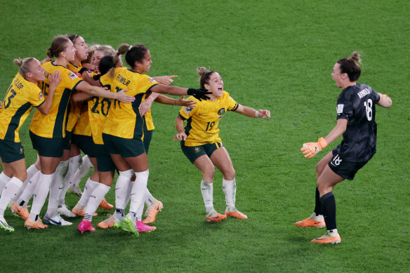 Mackenzie Arnold (right) embraces her Matildas teammates after Australia won the penalty shootout against France in the World Cup quarter-final.