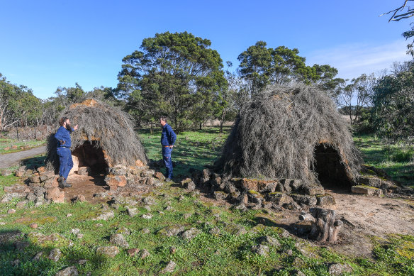 Budj Bim rangers Aaron Morgan and Leigh Boyer stand by replica stone houses in the UNESCO World Heritage-listed Budj Bim cultural landscape.