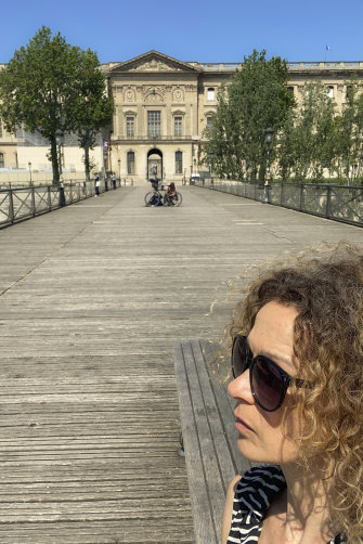 Elli Ioannou on the Ponts des Arts with the Louvre in the distance.