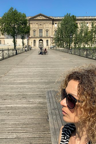 Elli Ioannou on the Ponts des Arts with the Louvre in the distance.