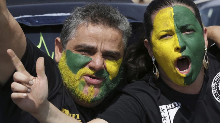 With their faces painted with the colours of Brazil, demonstrators shout slogans during a race in support of Jair Bolsonaro.