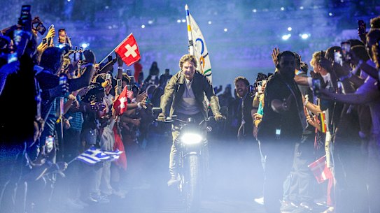 Tom Cruise rides the Olympic flag through the closing ceremony. 