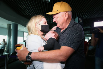 Cole meets his grandson Ted for the first time, with daughter Lauren, after they arrived on the first flight from Melbourne since the Queensland border reopened.