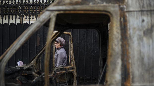 A woman and a burned out vehicle, near the Arc de Triomphe, in Paris, on Sunday, local time.