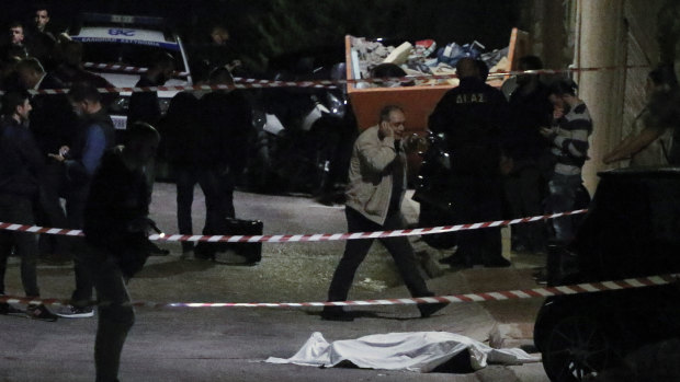 Police officers stand over the body of Greek-Australian John Macris who was shot dead outside his house in southern Athens. 