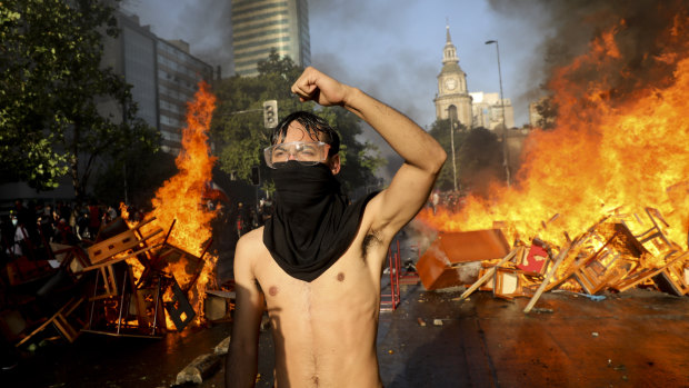 An anti-government protester stands guard at a burning barricade in Santiago, Chile, on Monday.