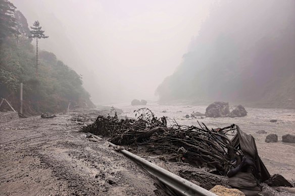 A muddy river bank with debris is seen near Gyirong Port in southwestern Tibet.