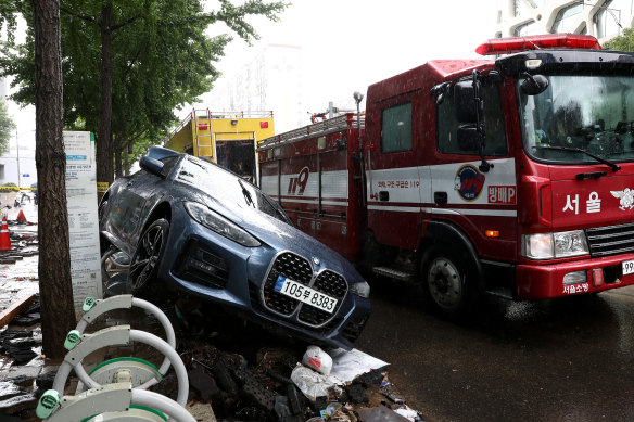 A vehicle is damaged on the sidewalk after floating in heavy rainfall in Seoul.
