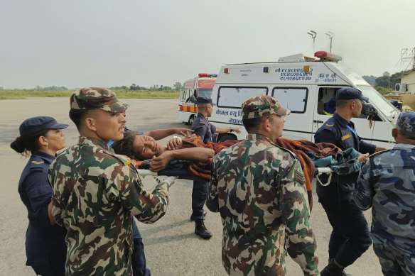 A woman airlifted from an earthquake-affected area is carried on a stretcher in Nepalgunj, Nepal, after daybreak.
