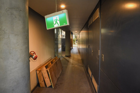 Signs hang from the ceiling of the entrance to number 19 Gadigal Avenue in Zetland. The building was condemned in 2018 because of fire safety defects and the owners of the top floors were forced to move out. Parts of the building were left unfinished and deteriorated. 
