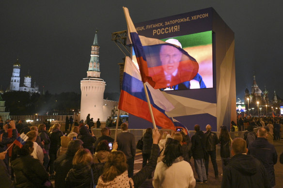 People watch on a large screen, as Russian President Vladimir Putin speaks during celebrations marking the incorporation of regions of Ukraine to join Russia, at the Red Square in Moscow, Russia. 