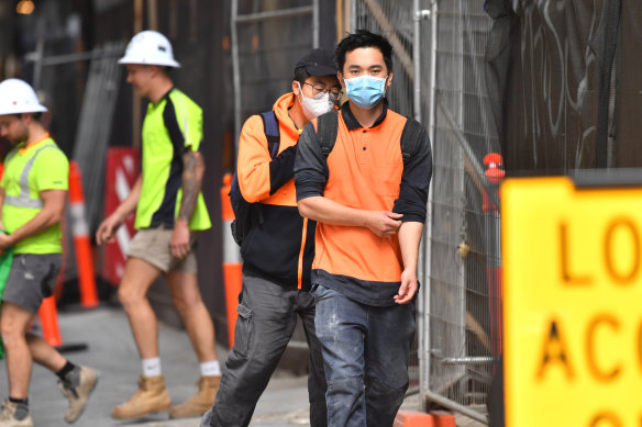 Construction workers in face masks leave a city building site earlier this week.