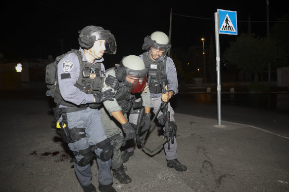 An Israeli police officer is taken away after being injured during clashes with Palestinian protesters in East Jerusalem on Friday.