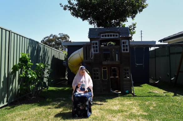 Hiam Zahab holds a photo of her daughter Nesrine Zahab, who is in al-Hawl camp in Syria with her child. Hiam hopes one day her grandchild can play in this backyard in Sydney.