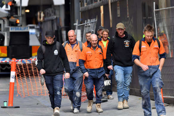 Knock off time: construction workers leave a city building site on Tuesday with far less than the advised 1.5 metres between them.