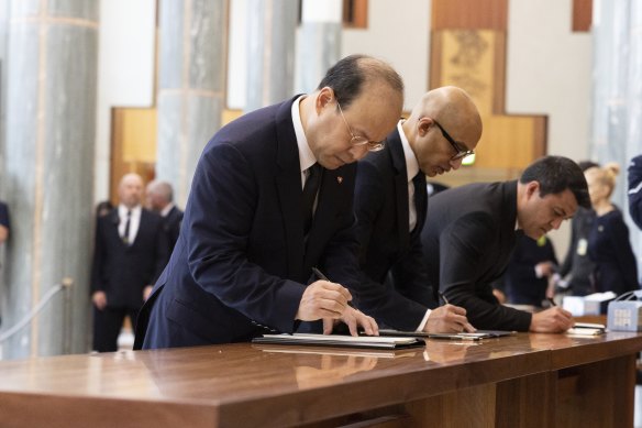 Chinese ambassador to Australia Xiao Qian signs the condolence book as he arrives.