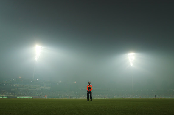 A security guard stands sentry amid smoke haze at Manuka Oval in Canberra.