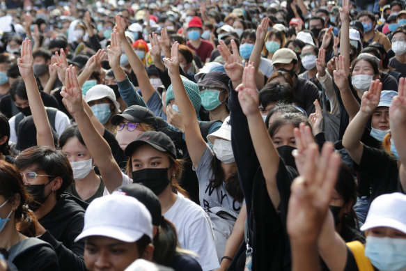 Pro-democracy students raise three-fingers, symbol of resistance salute, during a rally in Bangkok on August 16.