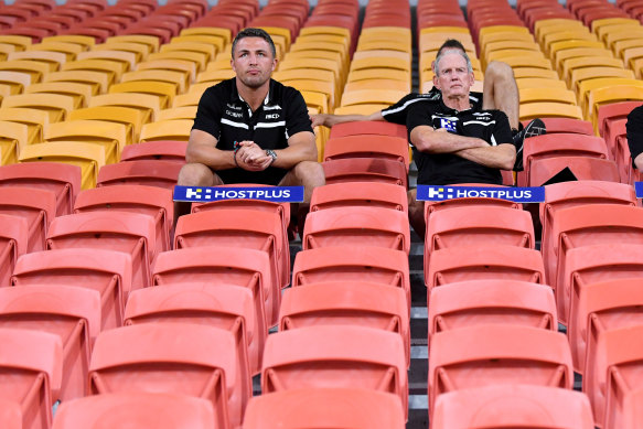 Rugby league in the coronavirus age: Souths’ Sam Burgess, Jason Demetriou and Wayne Bennett swap the coaches’ box for the grandstand at Suncorp Stadium on Friday night.