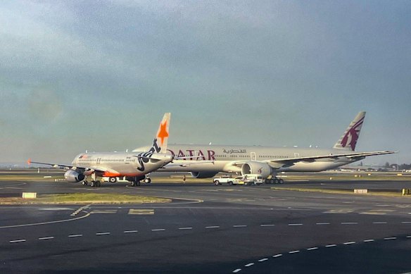 A Jetstar plane and a Qatar Airways plane are pictured on the runway at Sydney Airport. 