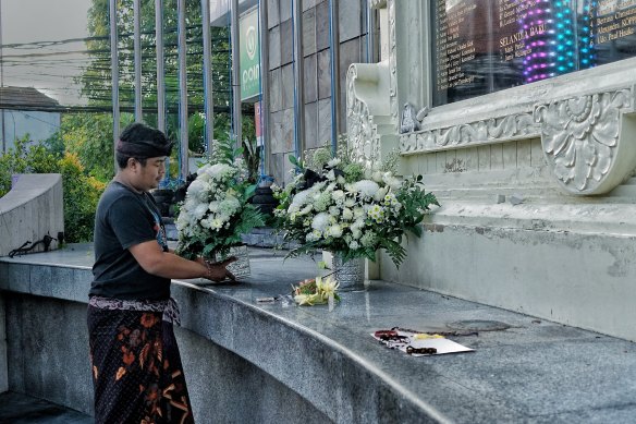 Made Bagus Aryadana places a flower bouquet at the Bali bombing monument for his late father. 