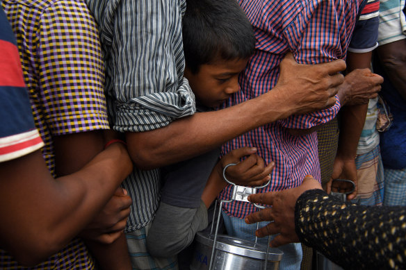 Rohingya refugees queue for a meal provided by a Turkish aid agency at a food distribution site in Shofiullah Kata Camp in Cox Bazar, Bangladesh.