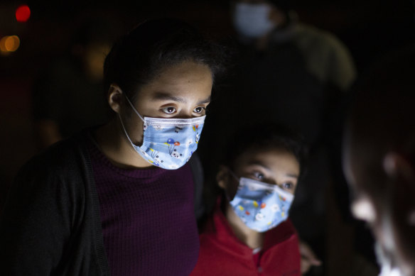 Fatima Nayeli, 13, left, and her sister, Cynthia Stacy, 8, answer questions from a US Border Patrol agent at an intake site after they were smuggled on an inflatable raft across the Rio Grande in Roma, Texas.