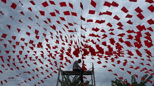 A man hangs up flags in Hanoi in preparation for Vietnam’s national day under a cloudy sky caused by Typhoon Kajiki on Monday.